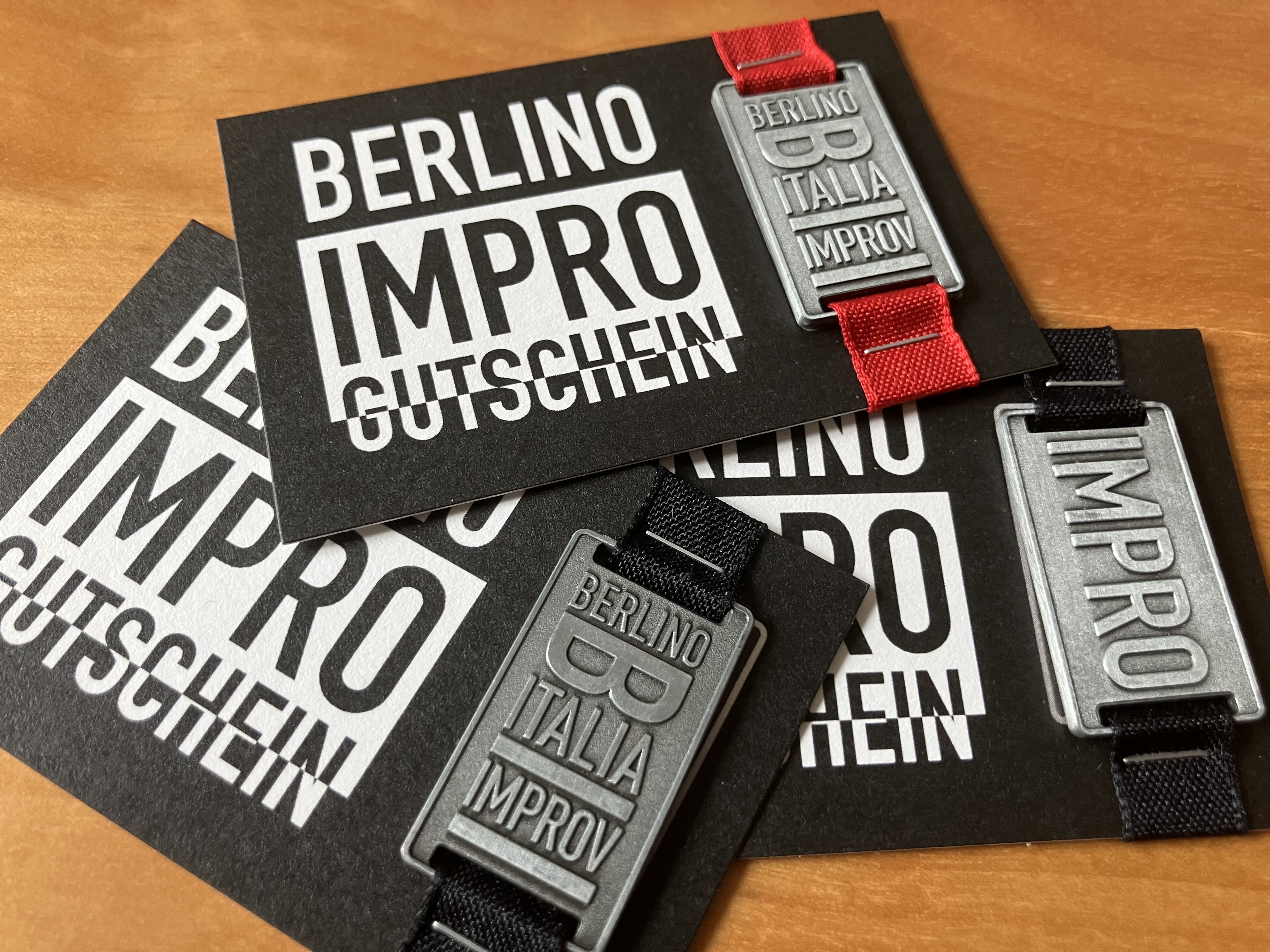 Berlino Impro Gutschein – cast metal token and gift cards on a wooden surface, Berlin improv gift voucher